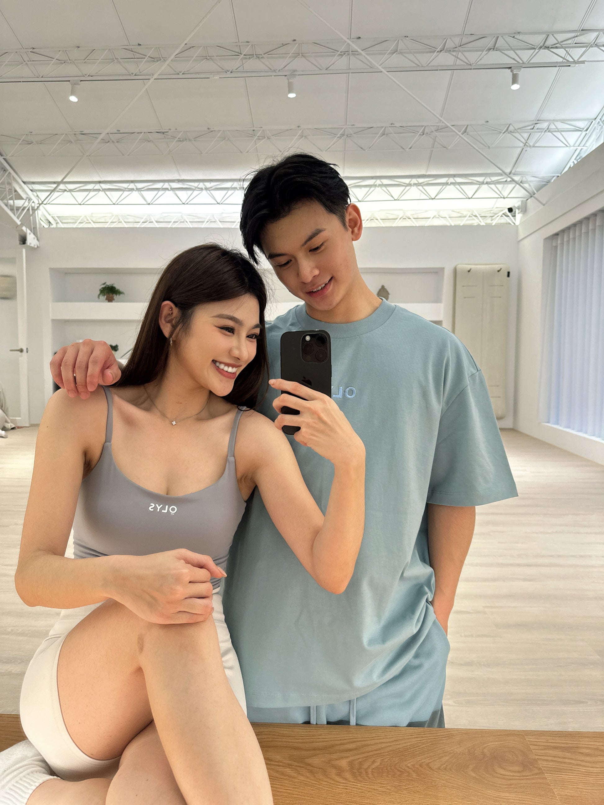 情侶穿搭,男生穿著 OLYS 刺繡 Logo 寬鬆 T 恤與短褲,女生穿著 OLYS 美背運動背心搭配高腰翹臀短褲,簡約舒適的情侶風格