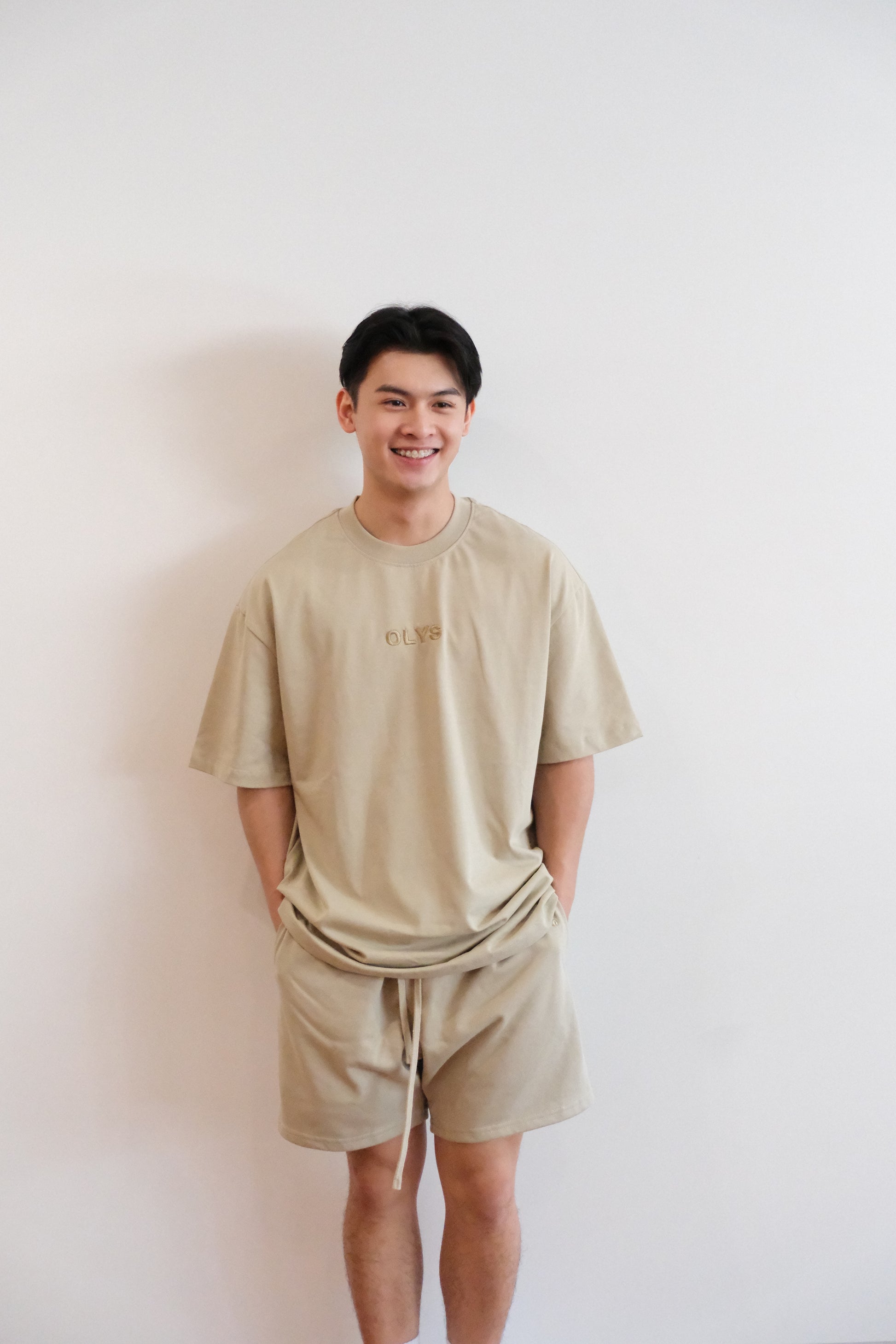 米色 OLYS 刺繡 Logo 寬鬆男裝 T 恤,搭配同色系棉質短褲,舒適休閒風格