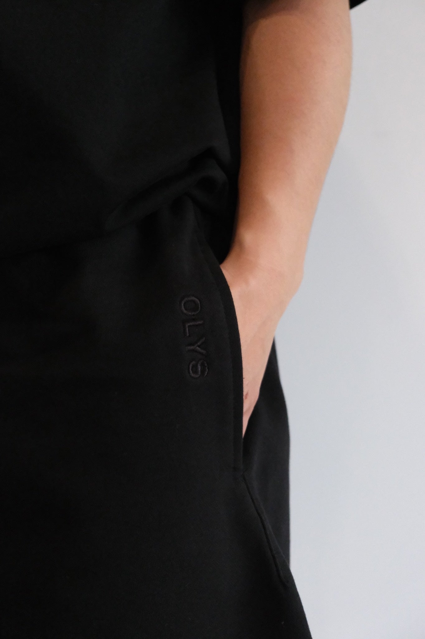 黑色 OLYS 刺繡 Logo 男裝 T 恤,搭配黑色棉短褲,極簡風格